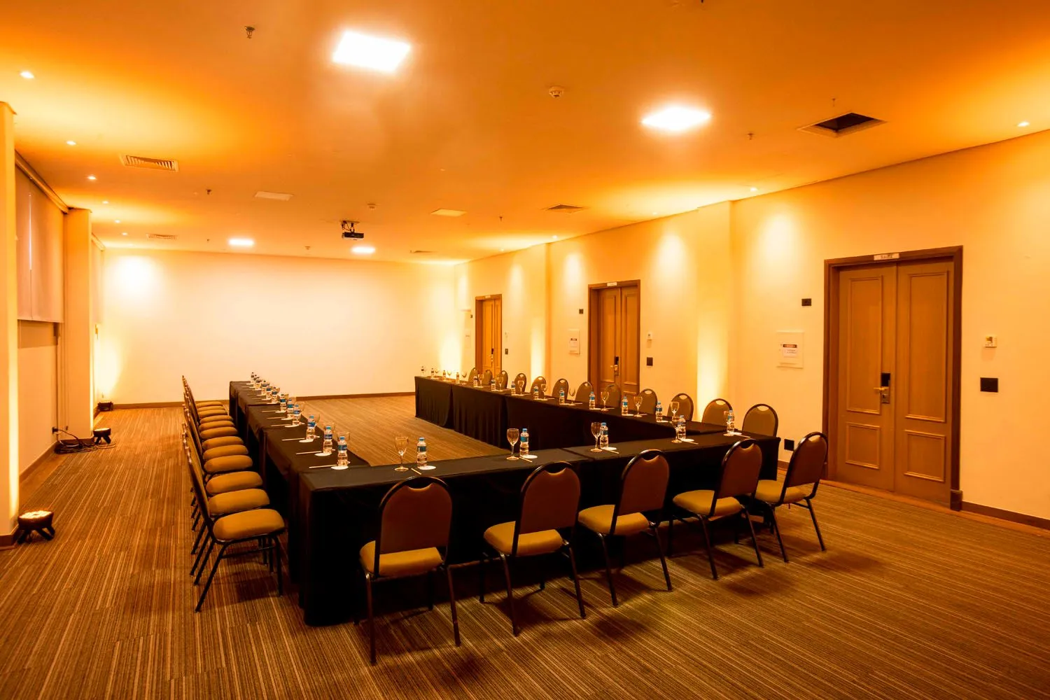 Uma grande sala de conferências com mesas e cadeiras preparadas para uma reunião.