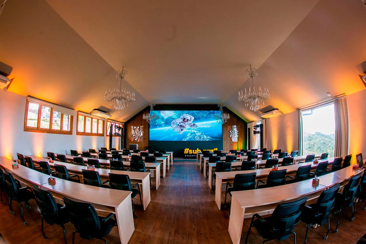 Uma grande sala de conferências com mesas e cadeiras e uma tela grande.