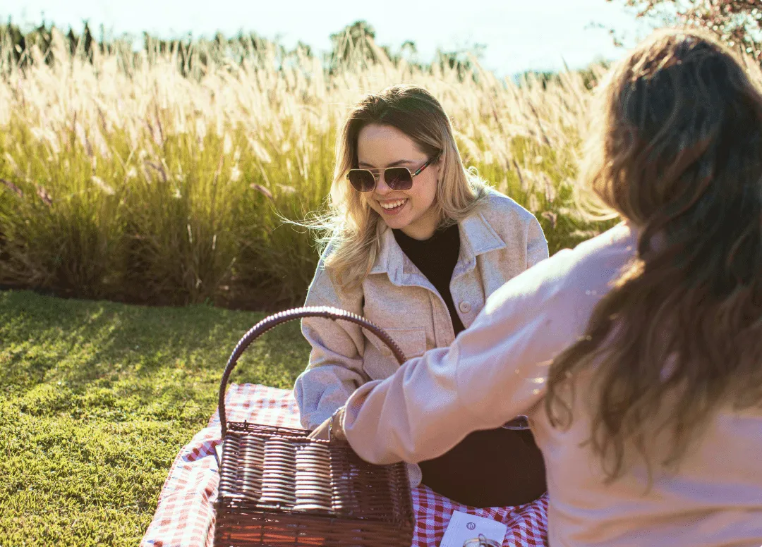 Duas mulheres estão fazendo um piquenique em um campo.